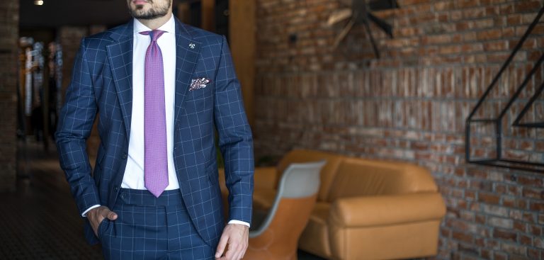 Man wearing a custom made blue checkered suit, white shirt and a purple tie.