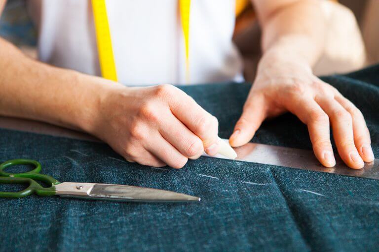 Tailor marking fabric with chalk after specific measurements