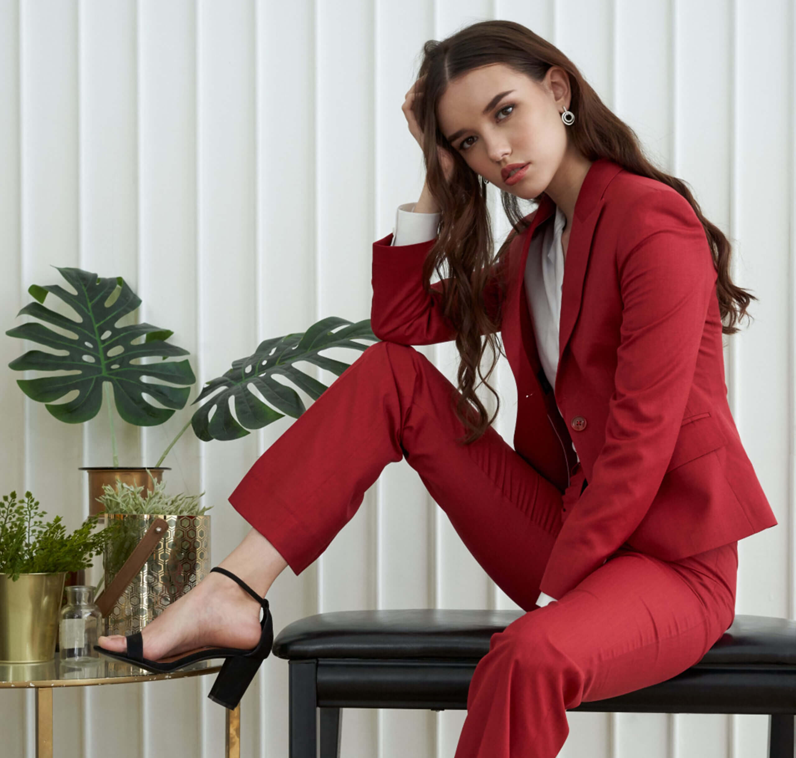 A young brown haired woman wearing tailored red trousers and a red jacket